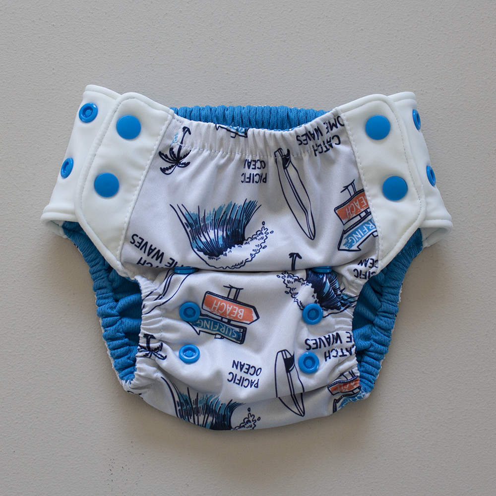 Kekoa flexible stretch wing swim nappy in Surfs Up print. From 4-19kg (9lbs - 42lbs) in a one size OSFM design. Bright electric blue AWJ lining.