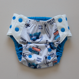 Kekoa flexible stretch wing swim nappy in Surfs Up print. From 4-19kg (9lbs - 42lbs) in a one size OSFM design. Bright electric blue AWJ lining.
